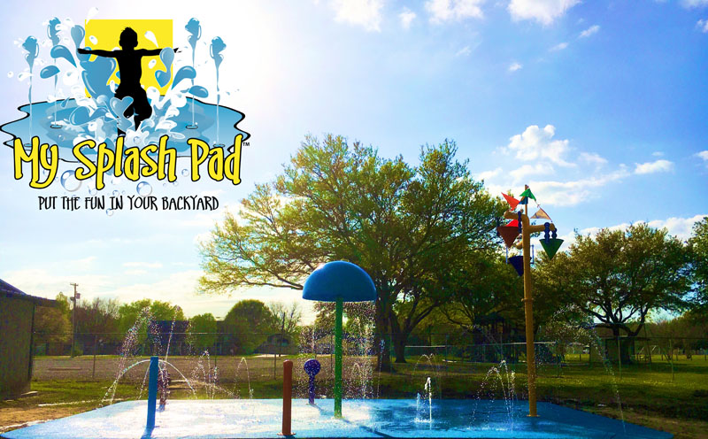 My Splash Pad water spray park aquatic play area playground equipment installer manufacturer. Blue sky, green grass. Above ground water play features installed by My Splash pad.
